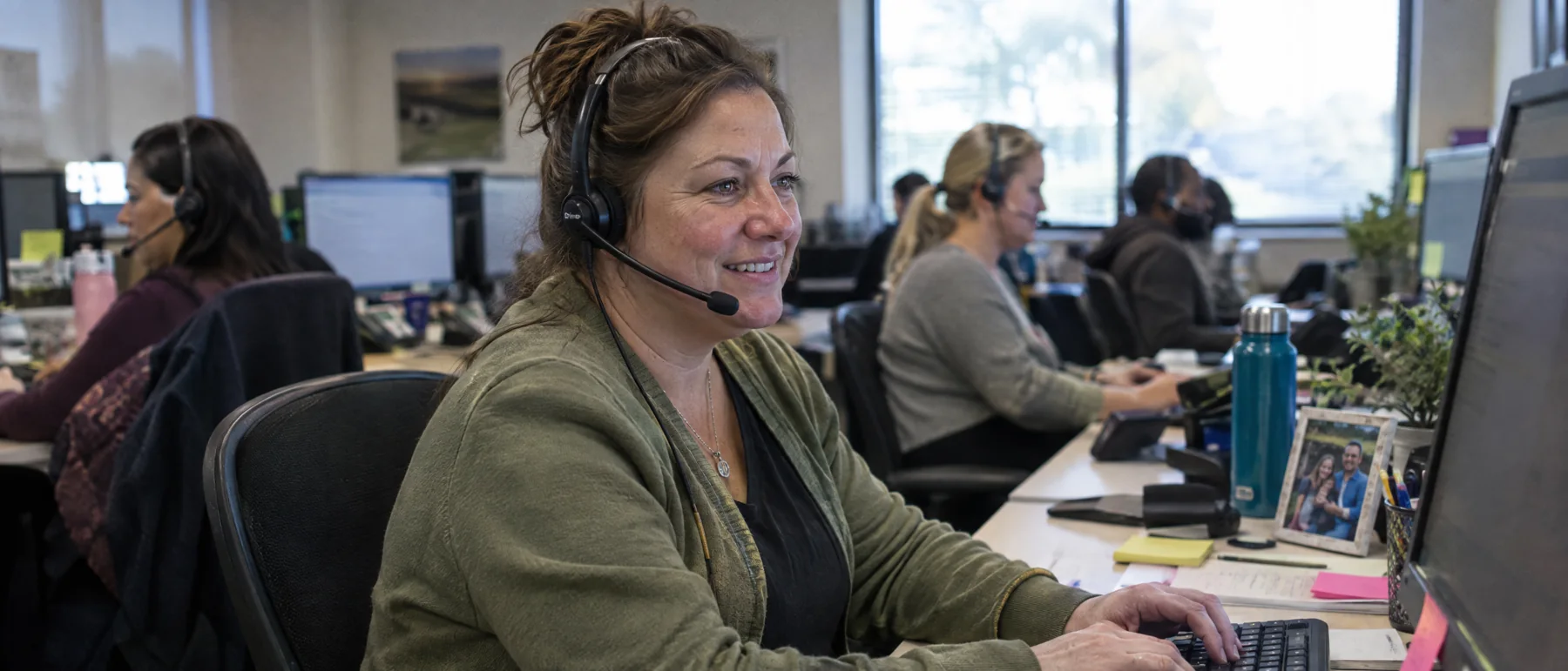 A phone sales rep wearing a headset takes an order in a call center